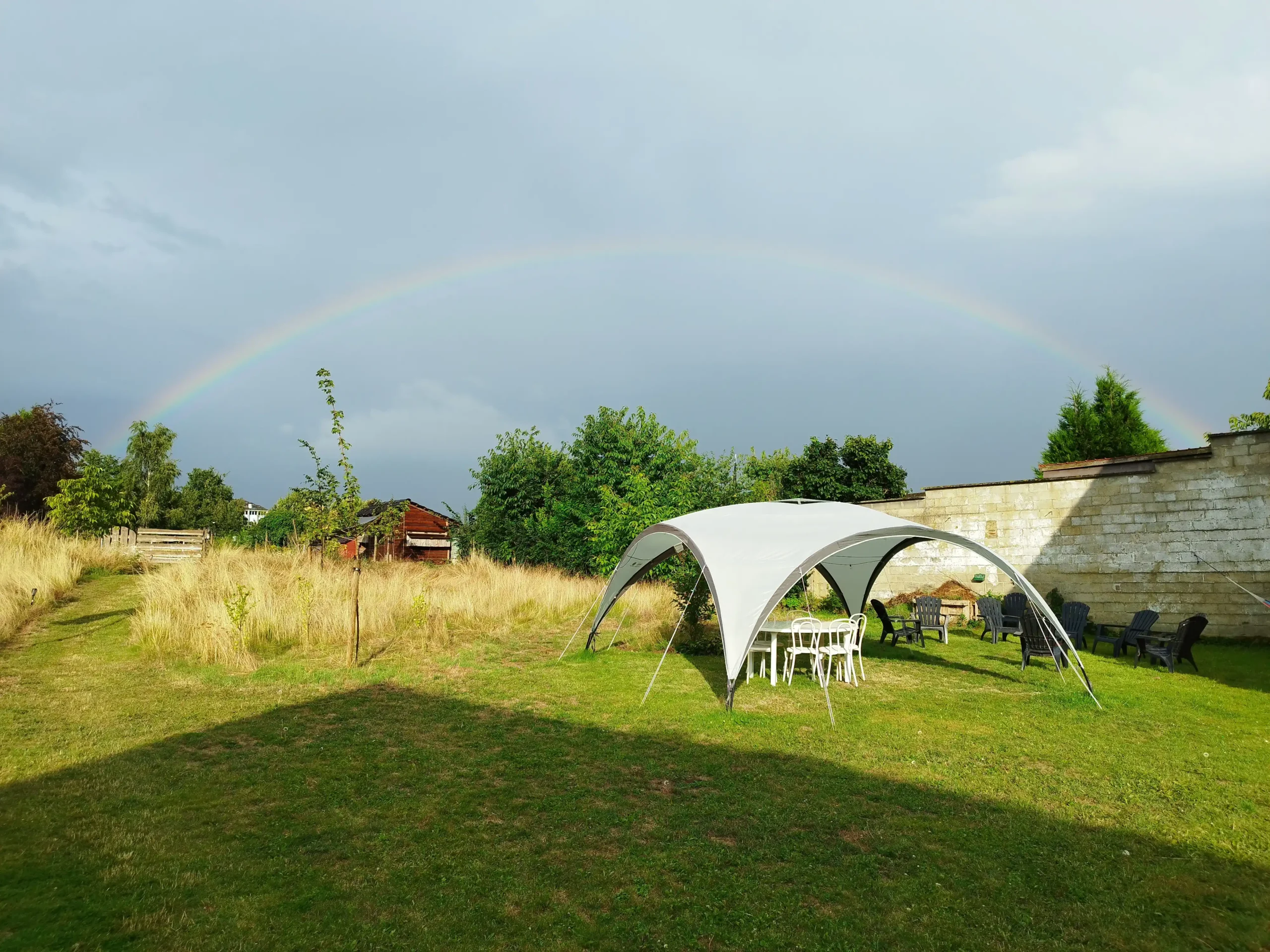 Regenboog boven de tuin met tent
